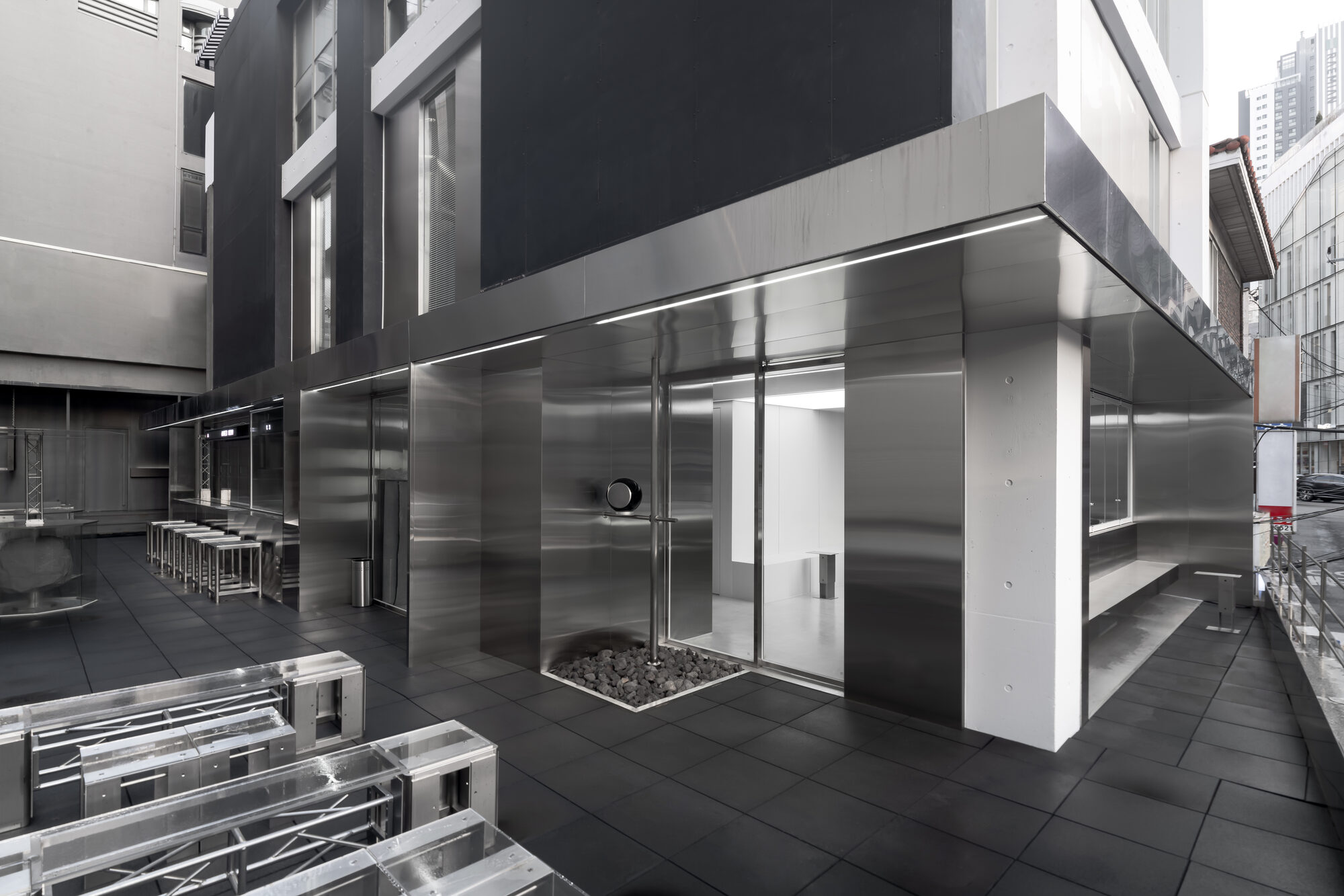 Street-level view of the WHS Lifting Center facade in Gangnam, Seoul — a modern stainless-steel clinic exterior on a black-stone paved plaza.